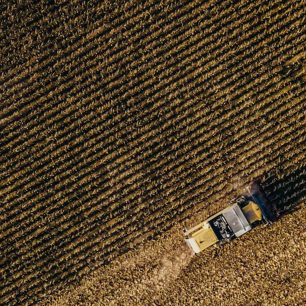 Overhead shot of a tractor driving across a cropfield.