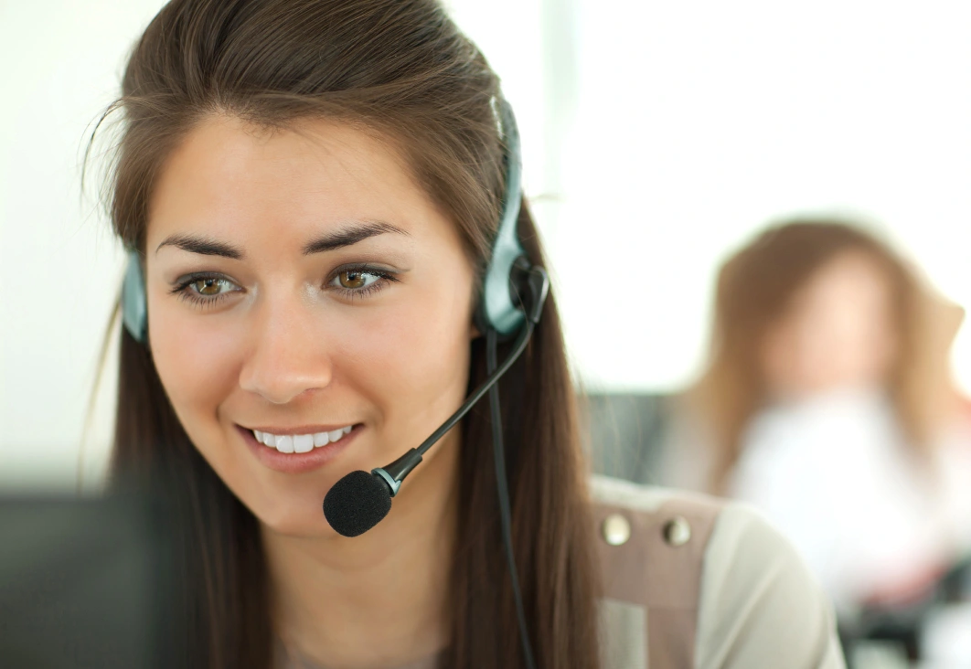 A woman in a headset (with microphone attached) smiles.