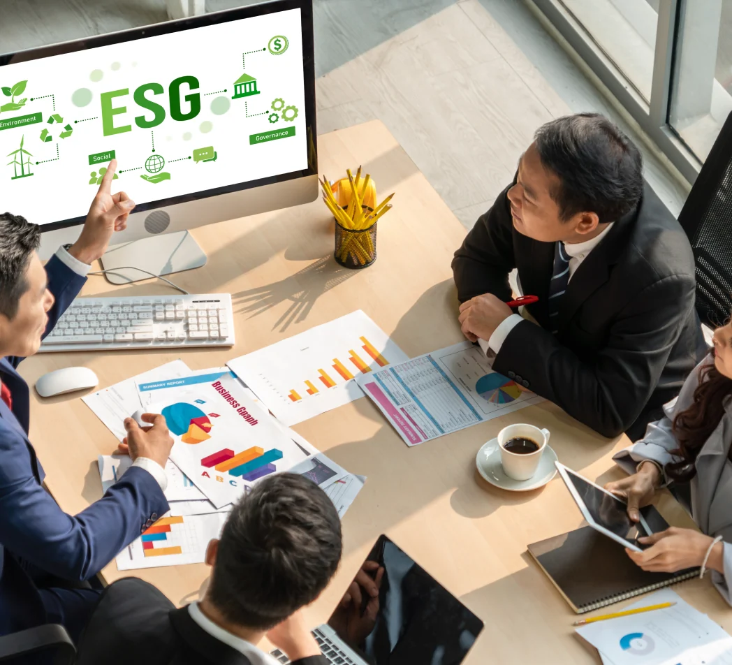 A group of people sit in a meeting room and discuss Environmental, Social, and Governance.