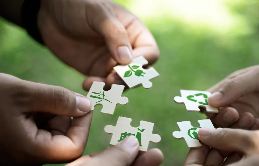 Close-up of five hands holding puzzle pieces.